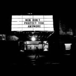 Black and white photograph of a lighted sign that reads "Men Don't Protect You Anymore"
